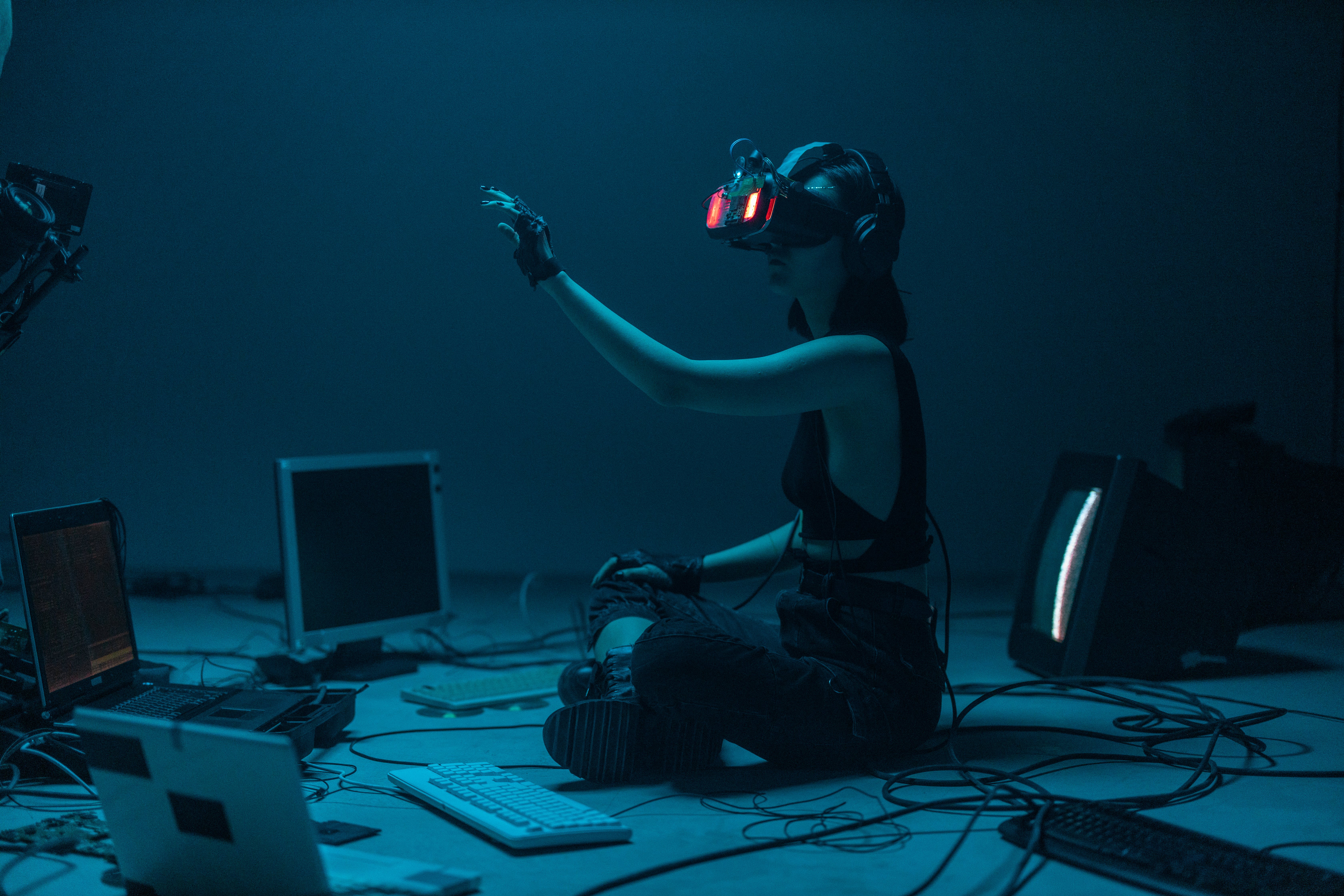 woman in a tank top using a VR headset surrounded by computer monitors